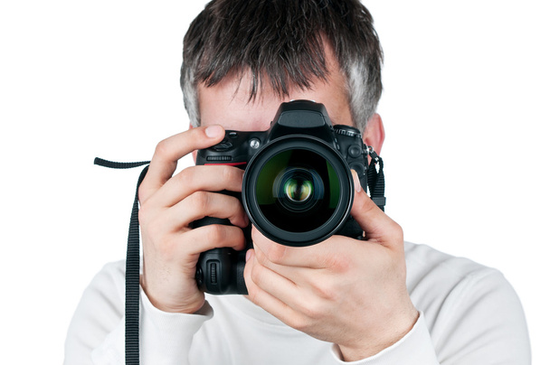 Young man with camera, isolated on white background, focus is on the lens - Foto, afbeelding