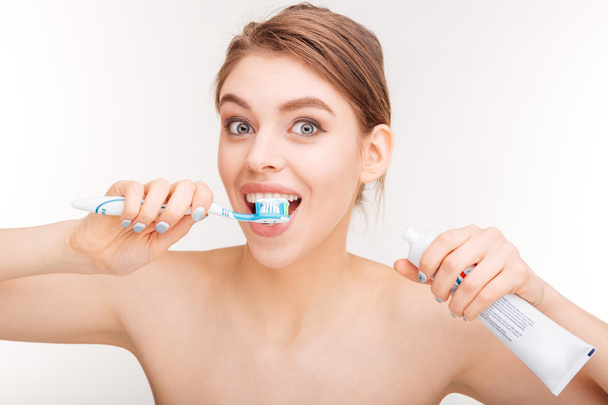 Content lovely woman brushing her teeth with toothpaste and toothbrush - 写真・画像