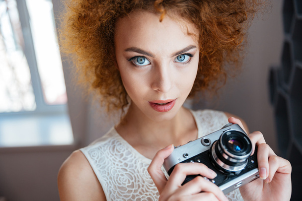 Красивая рыжая кудрявая молодая женщина фотограф с винтажной камерой
 - Фото, изображение