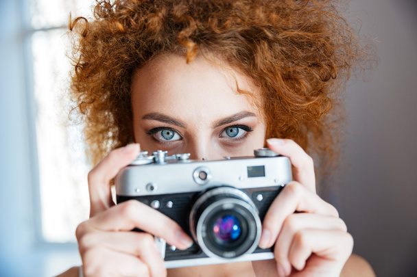 Attractive redhead woman photographer using old camera - Foto, Imagen