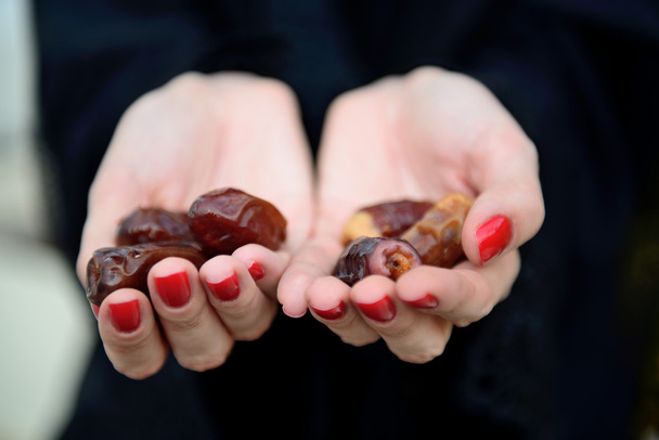 Emarati Arab woman holding dates in hand - Photo, Image