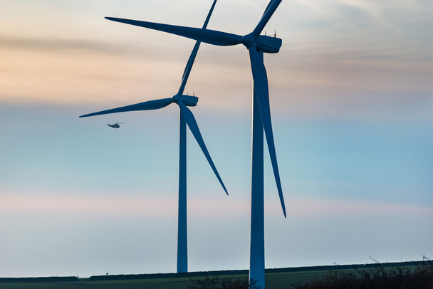Tuuliturbiinien ohi lentävä helikopteri
 - Valokuva, kuva