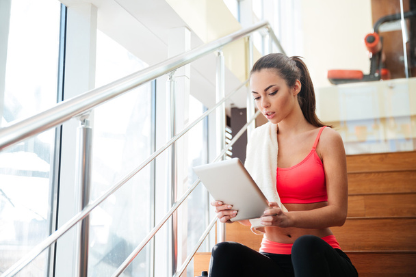Thougtful sportswoman using tablet after training in gym - Фото, зображення