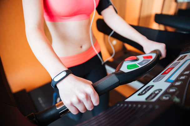 Treadmill used by young sportswoman with fitness tracker on  hand  - 写真・画像