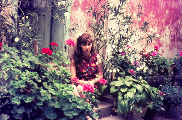 оригинальный винтажный слайд 1960-х годов, молодая женщина сидит в пышном саду
. - Фото, изображение