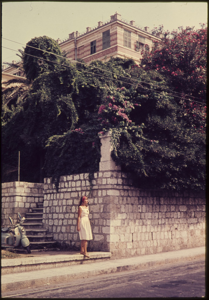 oryginalny kolor vintage slajdów z 1960 roku, kobiety stojącej w ulicy z rocznika motorower w tle. - Zdjęcie, obraz