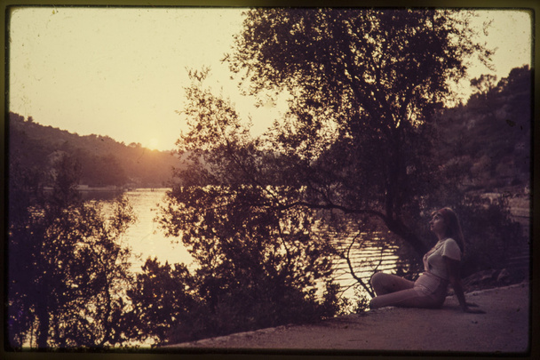 oryginalny kolor vintage slajdów z 1960 roku, młoda kobieta cieszy się zachód słońca nad jeziorem. - Zdjęcie, obraz