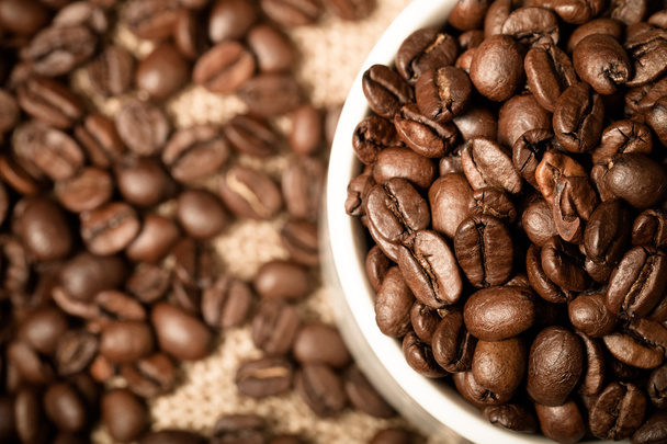 Cup, saucer and coffee beans on a burlap background. Shallow dep - Fotó, kép