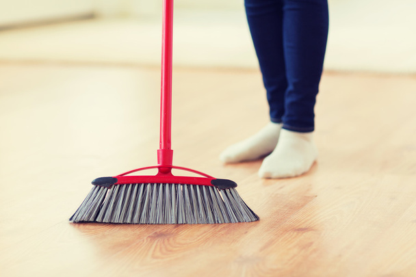 close up of woman legs with broom sweeping floor - Foto, Imagem