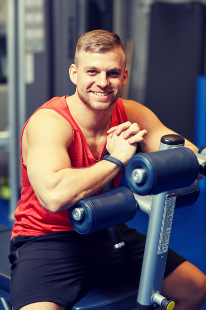 smiling man sitting on exercise bench in gym - Foto, afbeelding