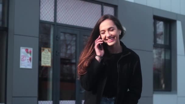 Muy hermosa chica hablando por teléfono y sonriendo. Chica de pie en la ciudad, al lado del restaurante
. - Imágenes, Vídeo