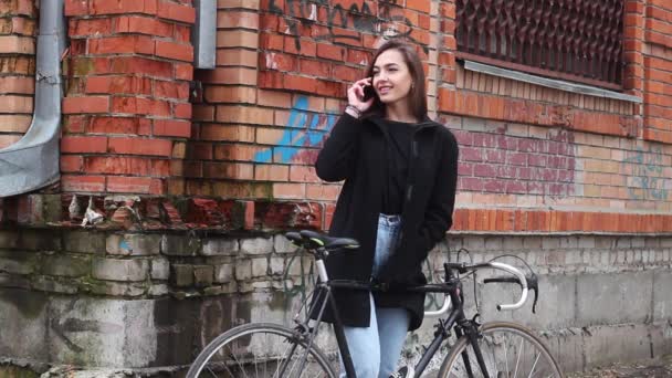 Kaunis tyttö polkupyörän kanssa, puhuu puhelimessa. tyttö on erittäin houkutteleva
. - Materiaali, video