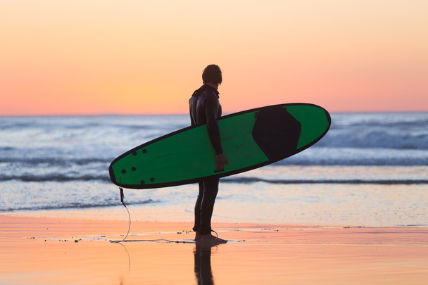Силуэт серфера на пляже с доской для серфинга
. - Фото, изображение