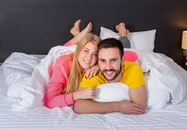 Young lovely couple lying and have fun in a bed - Foto, afbeelding