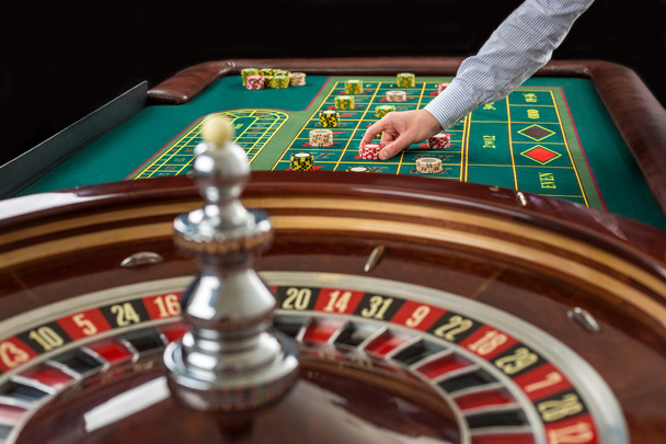 Roulette and piles of gambling chips on a green table. - Photo, Image