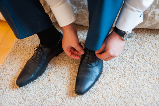Young man tying elegant shoes indoors - Fotó, kép