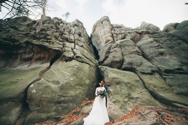 Gorgeous bride, groom kissing and hugging near the cliffs with stunning views - Fotografie, Obrázek