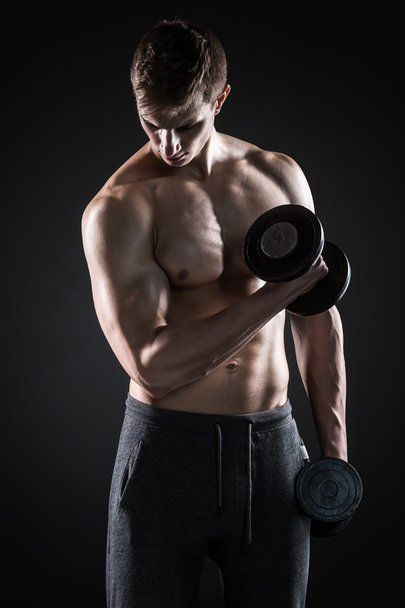 Man with naked torso and dumbbells on black background - Foto, immagini