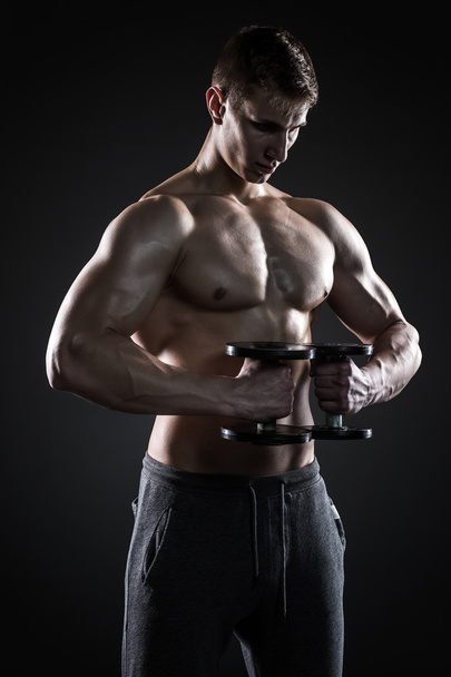 Mocný fitness muž ukazuje své krásné tělo s činkami - Fotografie, Obrázek