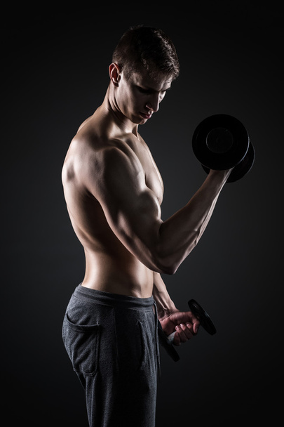 Мускулистый человек работает над упражнениями с гантелями на бицепсах
 - Фото, изображение