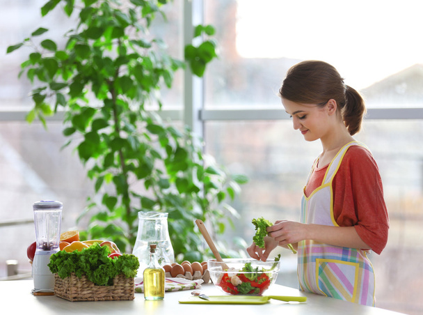 Молодая женщина готовит овощной салат
  - Фото, изображение