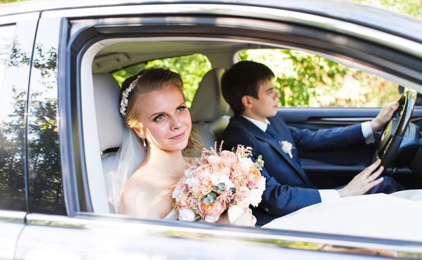 Nevěsta a ženich uvnitř auta. Oni jsou šťastní. - Fotografie, Obrázek