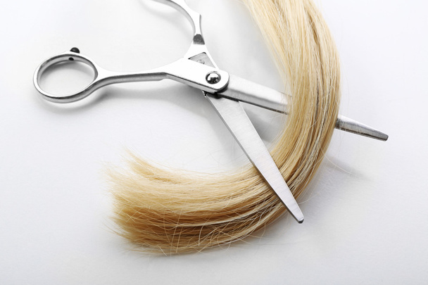 Friseurschere mit blonden Haarsträhnen, isoliert auf weiß - Foto, Bild
