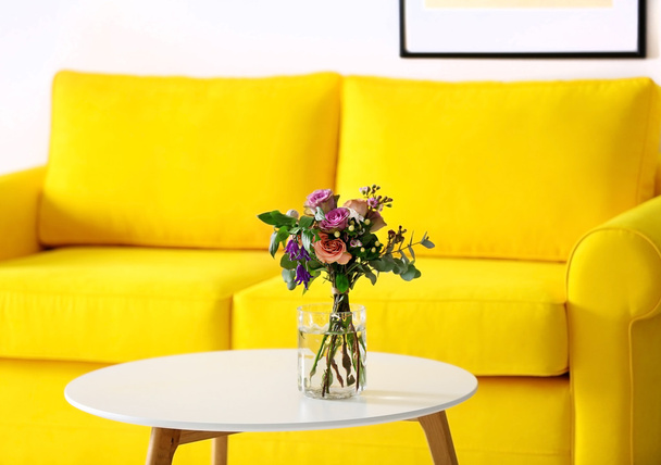 Pot van rozen op de tafel naast de gele Bank - Foto, afbeelding