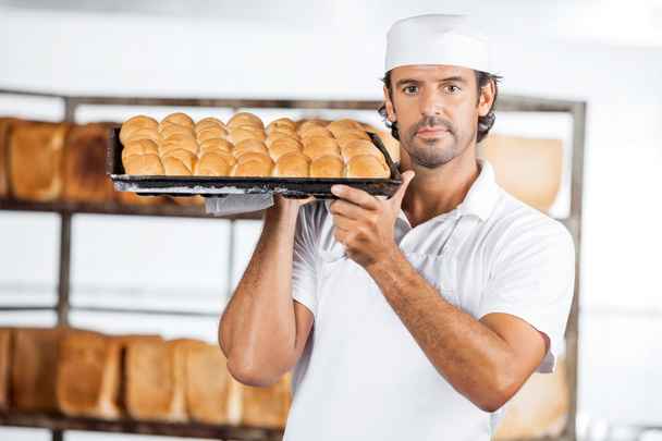 Baker Carrying Baking Tray On Shoulder At Bakery - Foto, Imagen