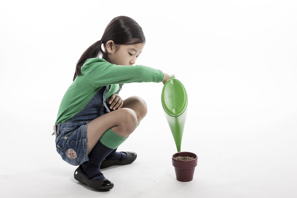 A child with watering tool and flower pot - Foto, Imagen
