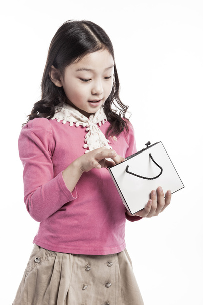 Egy gyerek visel rózsaszín blúz, fehér kendő Papír porzsák. - Fotó, kép