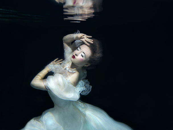 jeune fille en robe de luxe blanche longue sous l'eau sur le fond noir
 - Photo, image