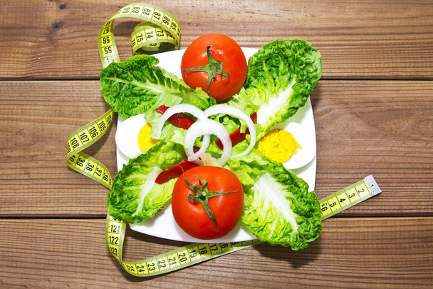 plate of salad and tape measure on wood - Foto, imagen