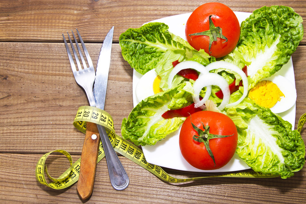 plate of salad and tape measure on wood - Foto, afbeelding
