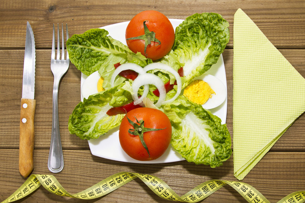 plate of salad and tape measure on wood - Foto, Imagen