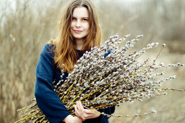 Portrait of a beautiful young girl with a huge armful of willow  - Foto, Imagen