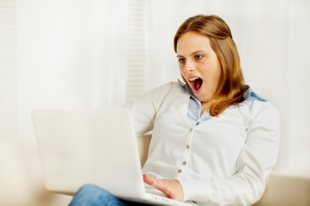 ενθουσιασμένος νεαρή γυναίκα χρησιμοποιώντας ένα φορητό υπολογιστή - Φωτογραφία, εικόνα
