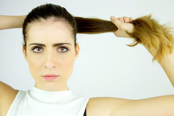 Beautiful female model pulling long hair in ponytail looking serious camera closeup - Foto, Imagem