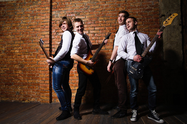 Portrait of young trendy musicians over a brick wall - Photo, Image