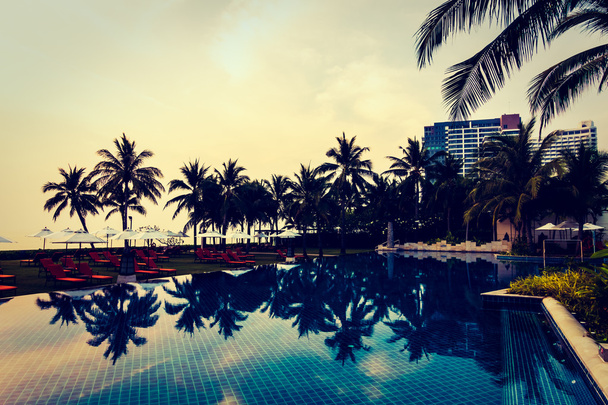 Silhouetten van palmbomen op zwembad - Foto, afbeelding