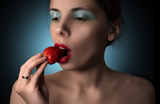 Sexy woman with red lips passionately eating strawberry. - 写真・画像