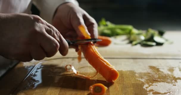 zkušený šéfkuchař uklízím biologickou mrkev ve starém tradičním stylu při extrémně pomalém pohybu - Záběry, video