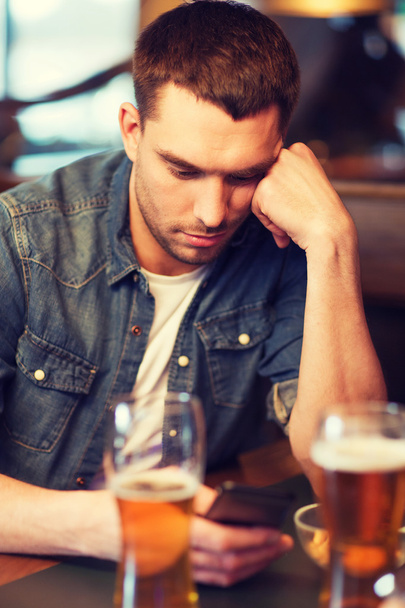 man with smartphone and beer texting at bar - Foto, Bild