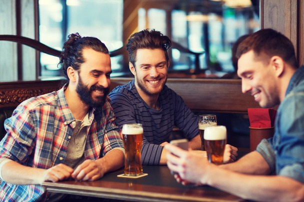 male friends with smartphone drinking beer at bar - Foto, immagini