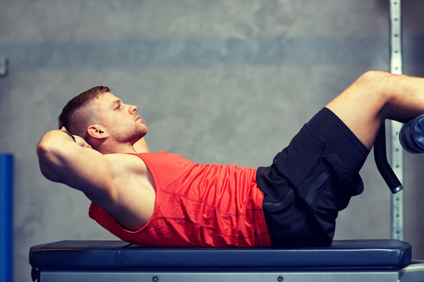 young man making abdominal exercises in gym - Foto, afbeelding