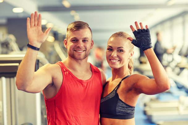 smiling man and woman waving hands in gym - Fotoğraf, Görsel