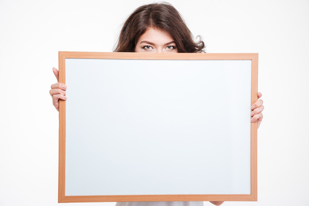 Jovem mulher espreitando de placa em branco
  - Foto, Imagem