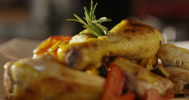 Εξαιρετικά αργή κίνηση του καβουρδισμένο πόδια κοτόπουλου με δεντρολίβανο και ψητά λαχανικά σερβίρονται σε λευκό πιάτο - Πλάνα, βίντεο
