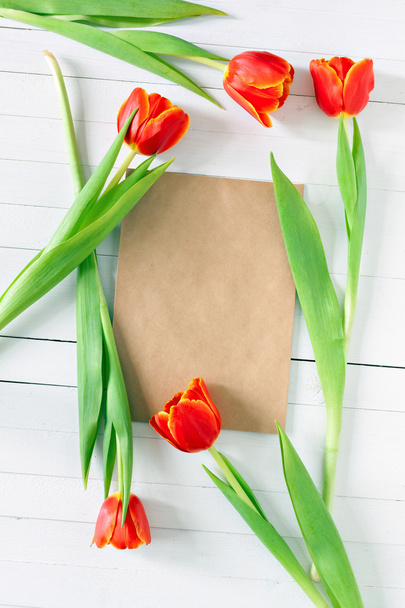 Colorful tulip bouquet and blank greeting card. Top view over white wooden table - Photo, image