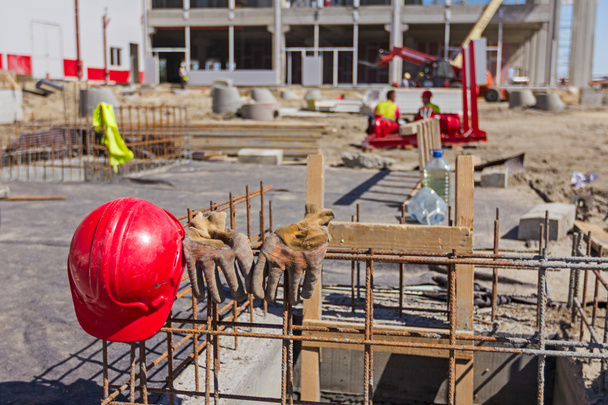 Рабочие перчатки с красной безопасностью, шлем на строительной площадке
 - Фото, изображение